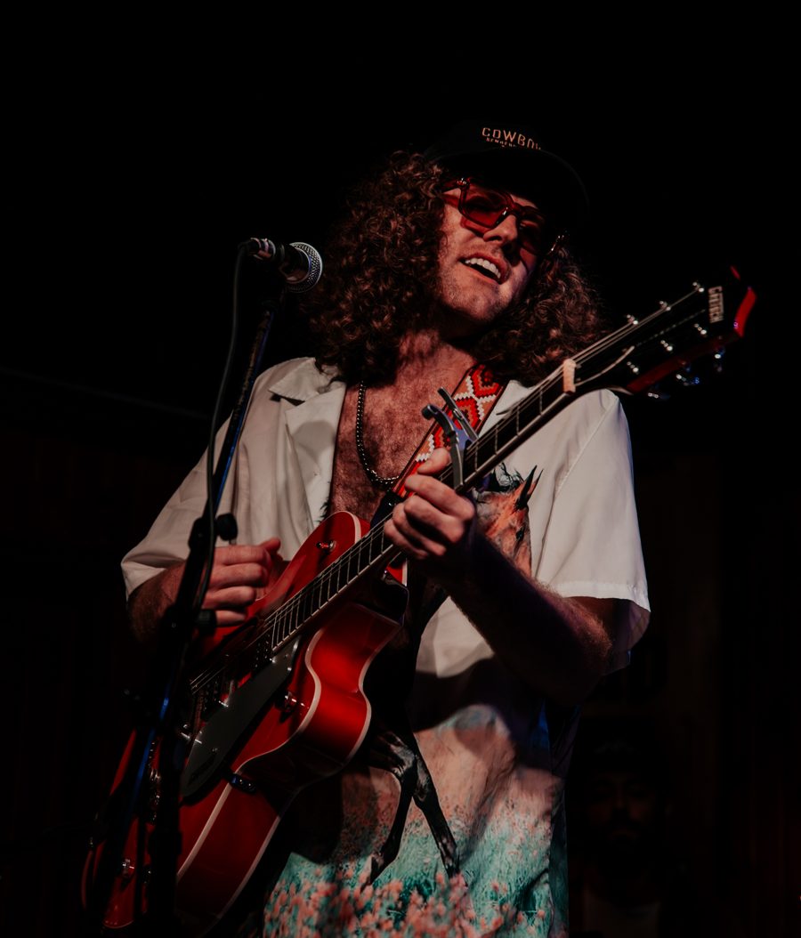 Ryan Salata playing a red hollow-body guitar on stage